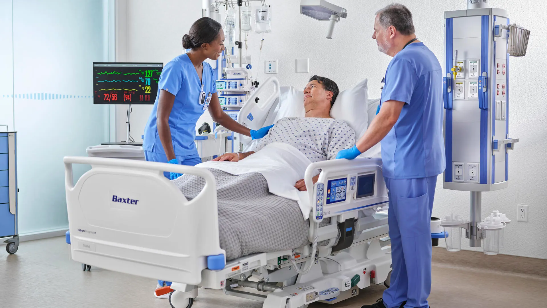 A patient in the ICU being assisted by two healthcare workers