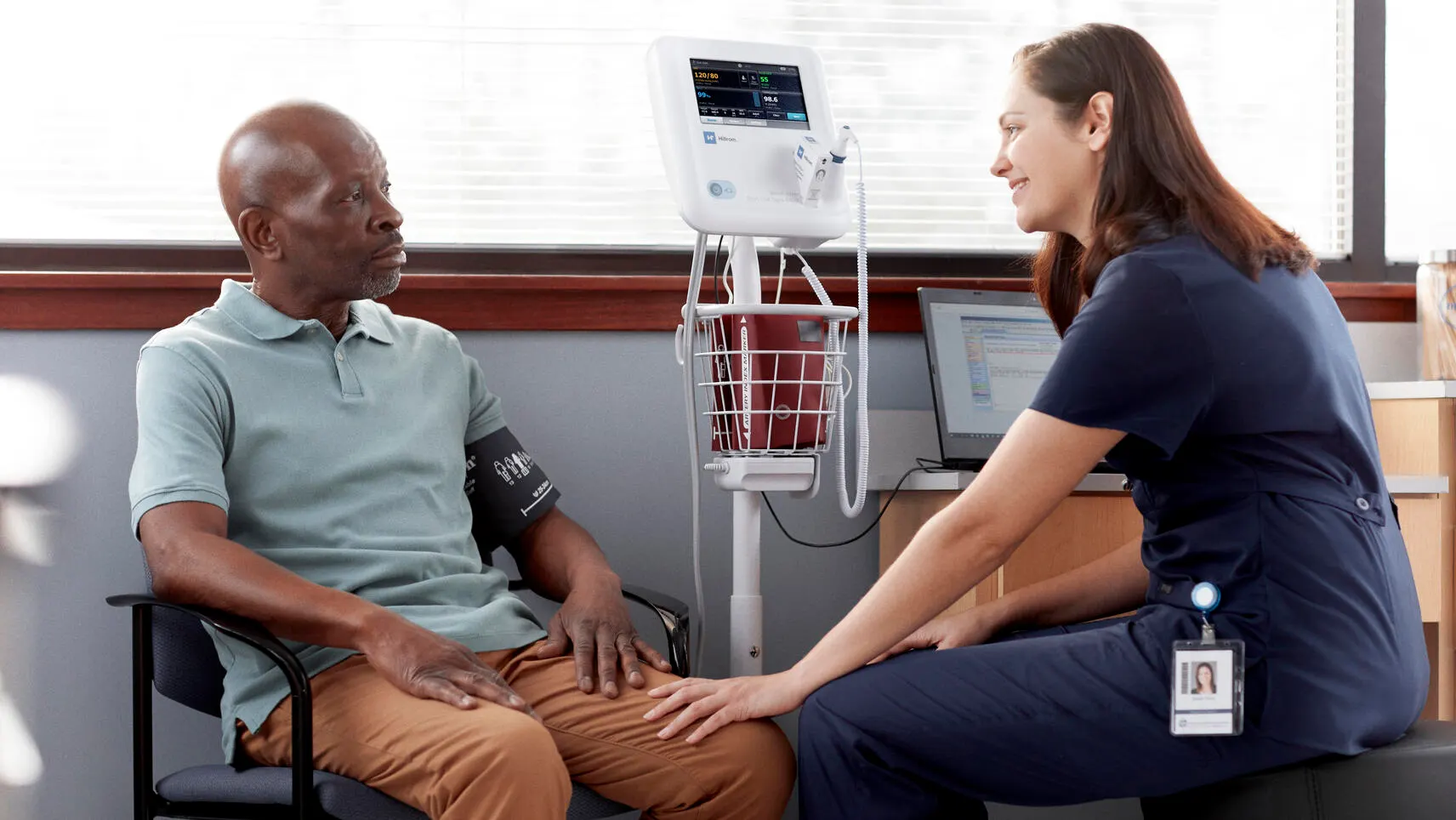 A healthcare worker comforts a patient attached to a vital signs monitor