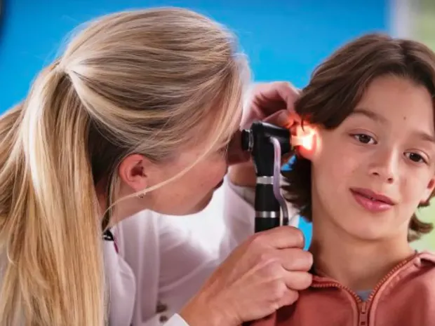 A nurse performing an ear examination on a young boy using Welch Allyn Macroview Plus.
