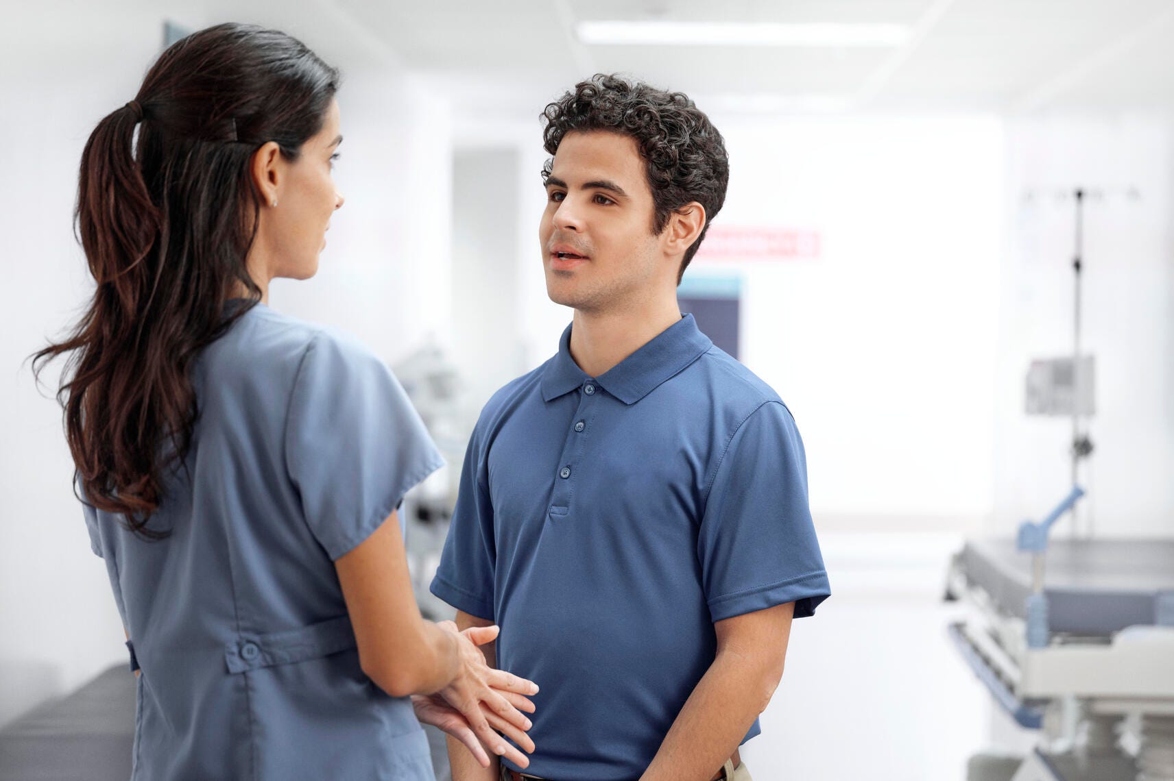 Clinician and technician converse in a hospital hallway