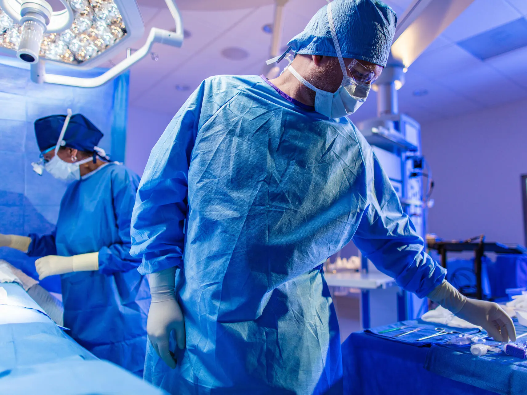 Two surgeons in scrubs operating on a patient