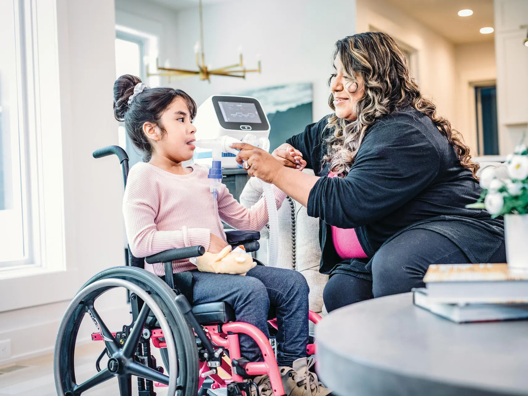 Child in a wheelchair receiving respiratory therapy with Volara home with assistance from an adult